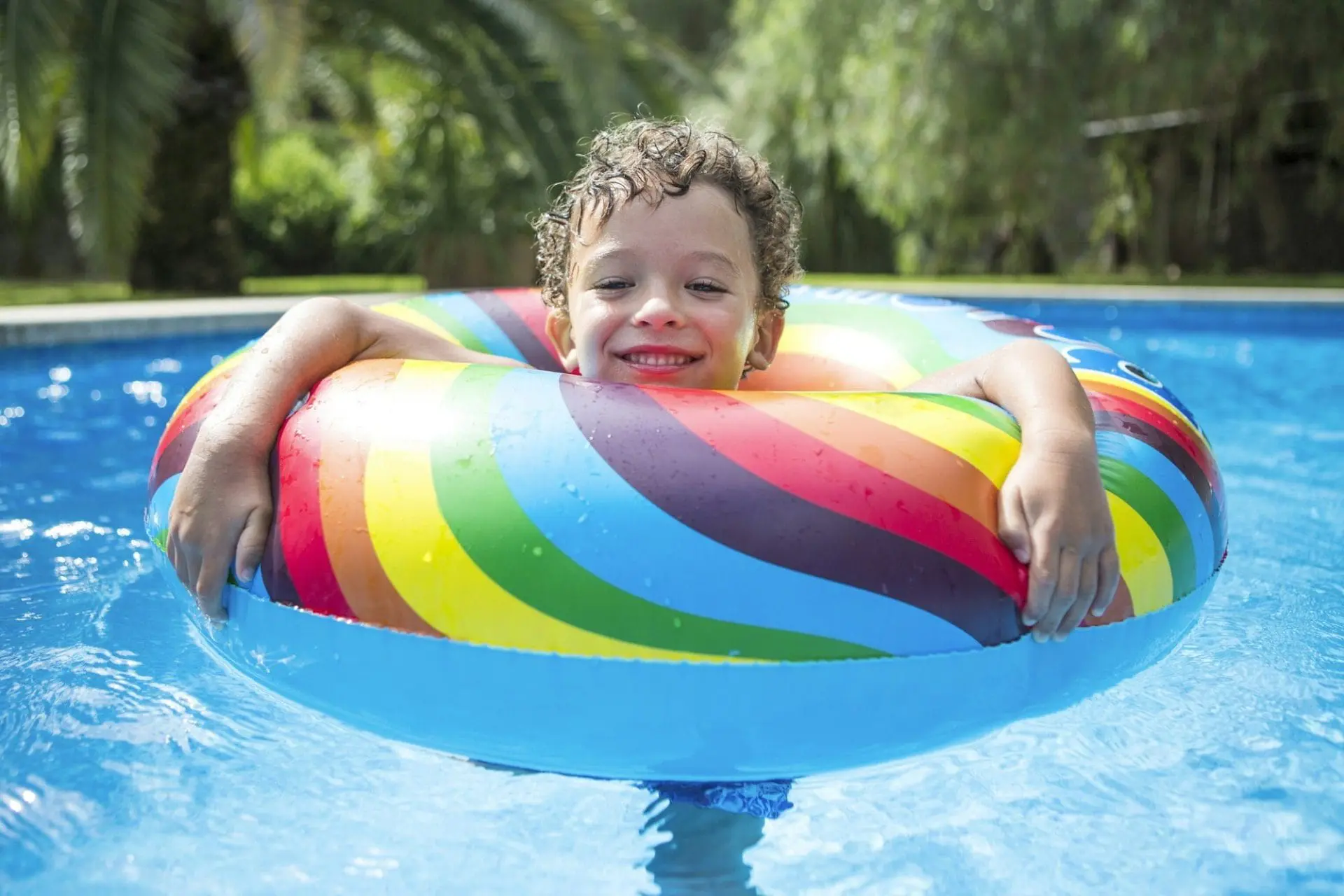 Boy with inflatable ring in outdoor swimming pool, portrait